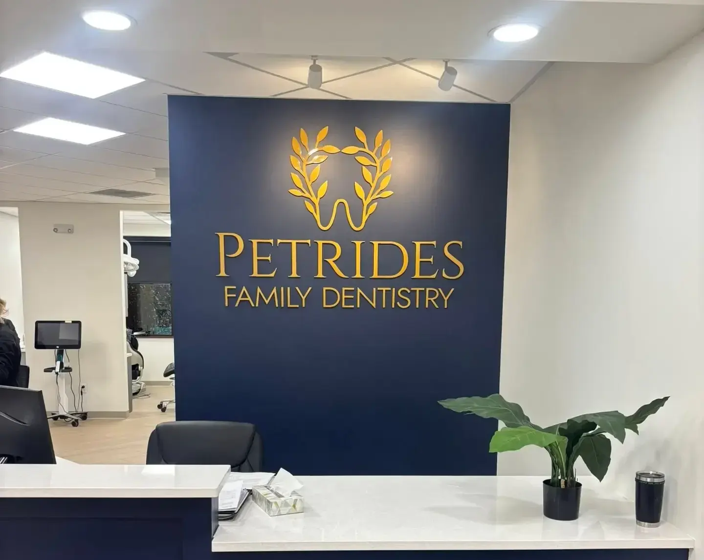 Petrides Family Dentistry reception sign with a gold dimensional logo on a navy wall