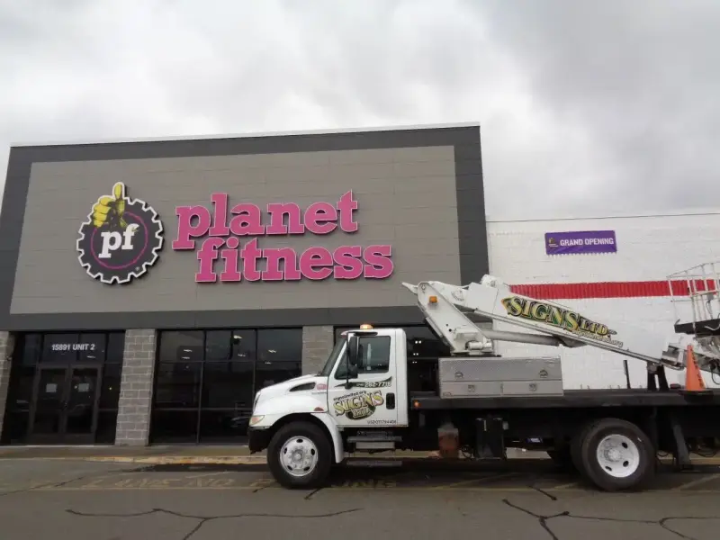 Signs Limited bucket truck at a Planet Fitness storefront with illuminated channel letters